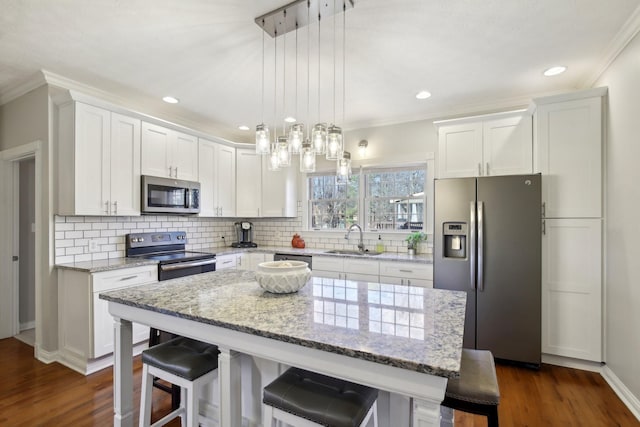 kitchen featuring pendant lighting, a center island, a kitchen bar, white cabinetry, and appliances with stainless steel finishes