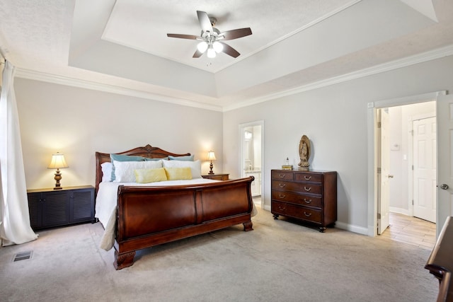 bedroom featuring light carpet, ceiling fan, a tray ceiling, and ornamental molding