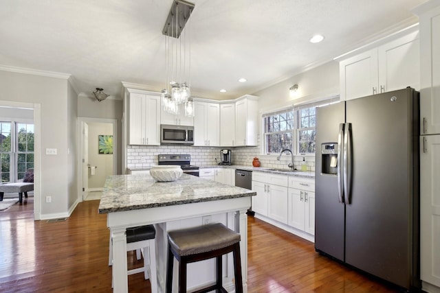 kitchen with appliances with stainless steel finishes, white cabinetry, a center island, and sink