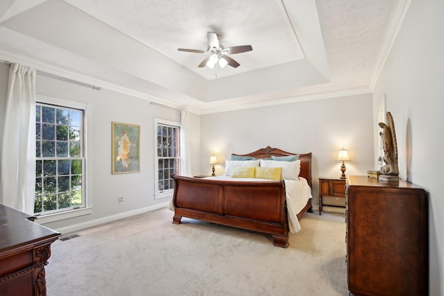 carpeted bedroom featuring ornamental molding, a textured ceiling, ceiling fan, and a tray ceiling