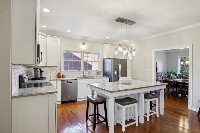 kitchen with a center island, white cabinetry, decorative backsplash, hanging light fixtures, and appliances with stainless steel finishes