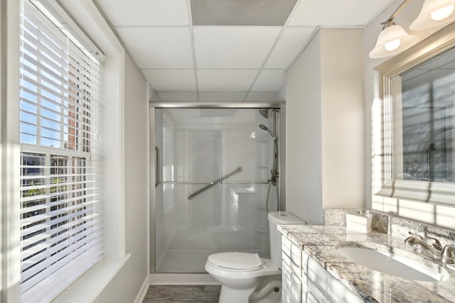 bathroom with toilet, a paneled ceiling, a shower with door, wood-type flooring, and vanity