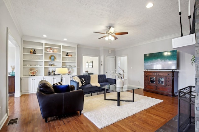 living room featuring hardwood / wood-style flooring, a textured ceiling, ornamental molding, and ceiling fan