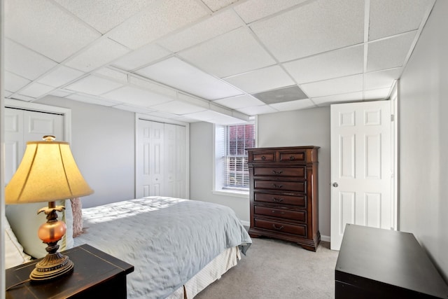 bedroom featuring light colored carpet, a closet, and a paneled ceiling