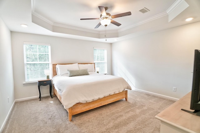 carpeted bedroom featuring a raised ceiling, multiple windows, ceiling fan, and ornamental molding