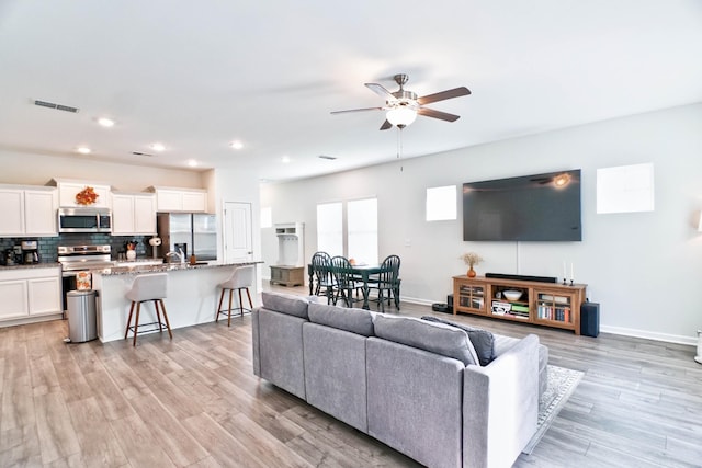 living room featuring light wood-type flooring and ceiling fan