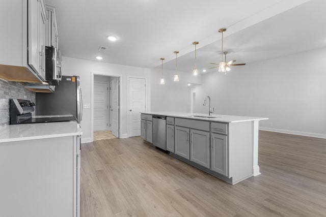 kitchen featuring decorative light fixtures, backsplash, appliances with stainless steel finishes, ceiling fan, and sink