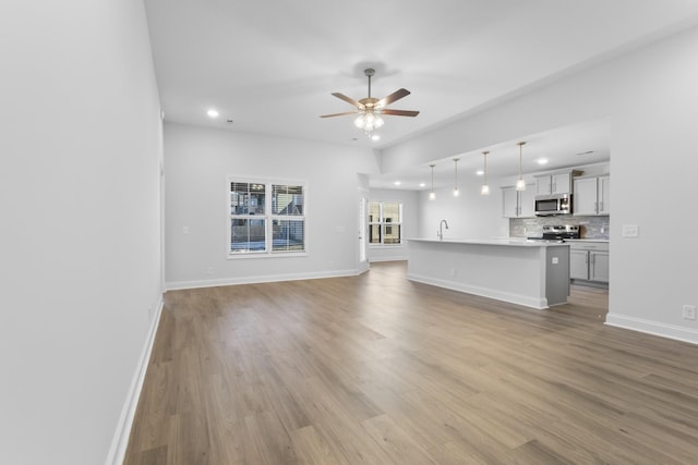 unfurnished living room featuring ceiling fan, light hardwood / wood-style floors, and sink