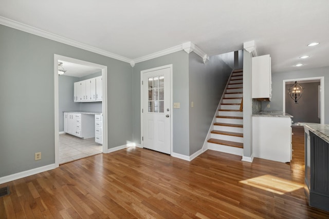 foyer with crown molding and light hardwood / wood-style flooring