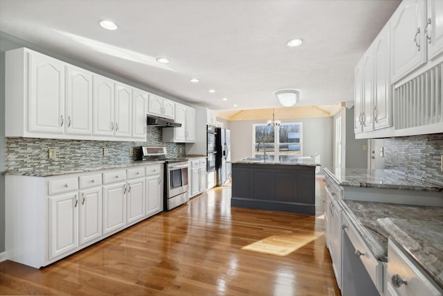 kitchen featuring pendant lighting, stainless steel range with electric cooktop, white cabinets, tasteful backsplash, and stone countertops