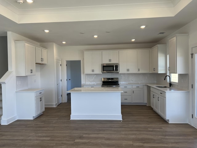 kitchen featuring appliances with stainless steel finishes, a sink, white cabinetry, and a center island