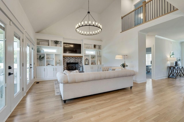 living room with a chandelier, a fireplace, high vaulted ceiling, and light hardwood / wood-style floors