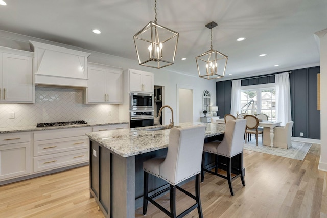 kitchen featuring appliances with stainless steel finishes, sink, white cabinetry, and an island with sink