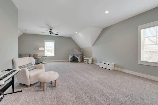 sitting room with ceiling fan, light colored carpet, and vaulted ceiling