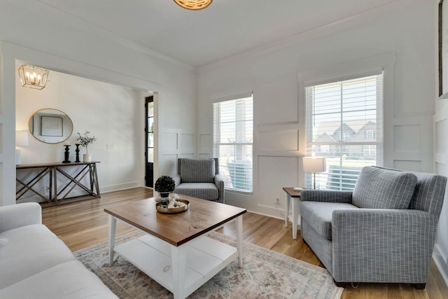 living room featuring light hardwood / wood-style floors, an inviting chandelier, and ornamental molding