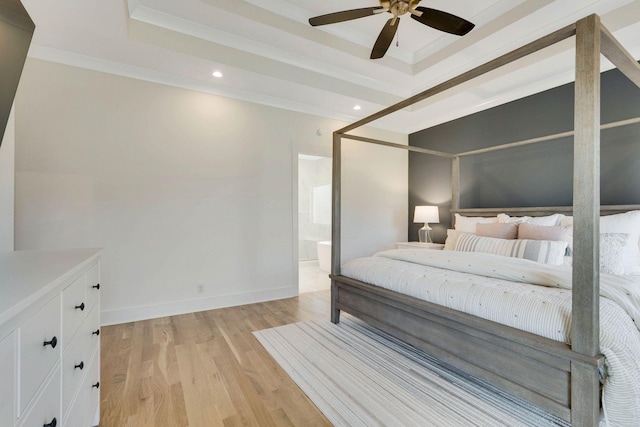 bedroom with a raised ceiling, crown molding, ensuite bath, light hardwood / wood-style flooring, and ceiling fan