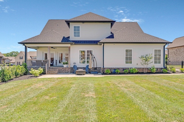 back of house with ceiling fan, covered porch, and a yard