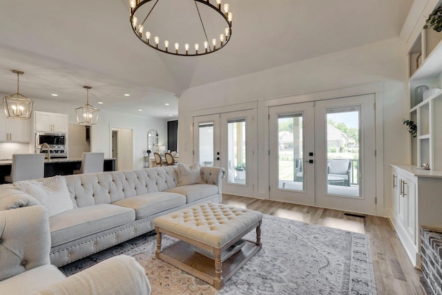 living room featuring french doors, light hardwood / wood-style floors, and lofted ceiling