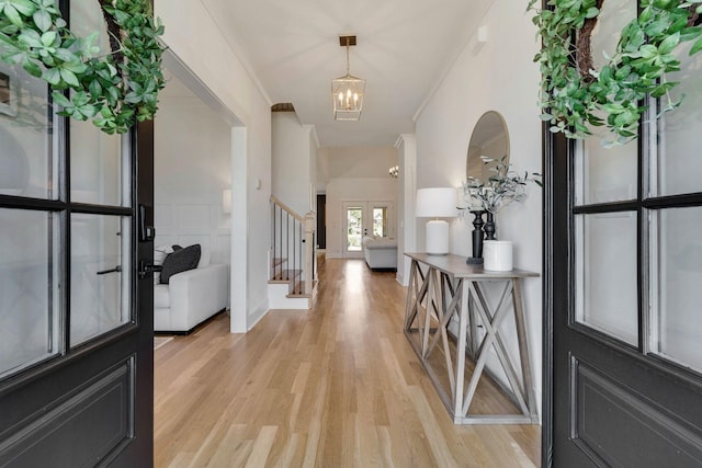 entrance foyer featuring a chandelier, french doors, light hardwood / wood-style floors, and ornamental molding