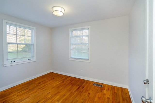 empty room with hardwood / wood-style floors and plenty of natural light