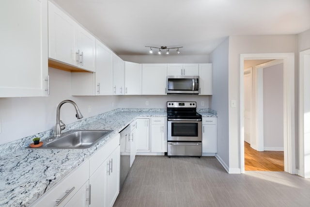 kitchen featuring light stone countertops, stainless steel appliances, white cabinetry, and sink