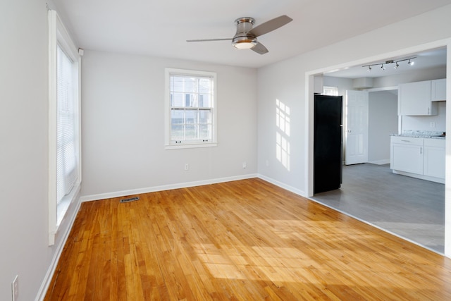 spare room with light hardwood / wood-style floors, ceiling fan, and a healthy amount of sunlight