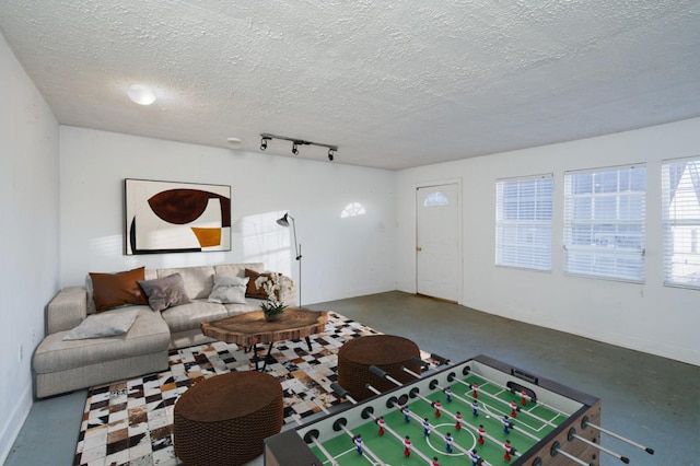 living room with rail lighting, concrete flooring, and a textured ceiling