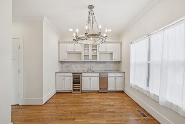 kitchen with wine cooler, white cabinetry, decorative light fixtures, and a wealth of natural light