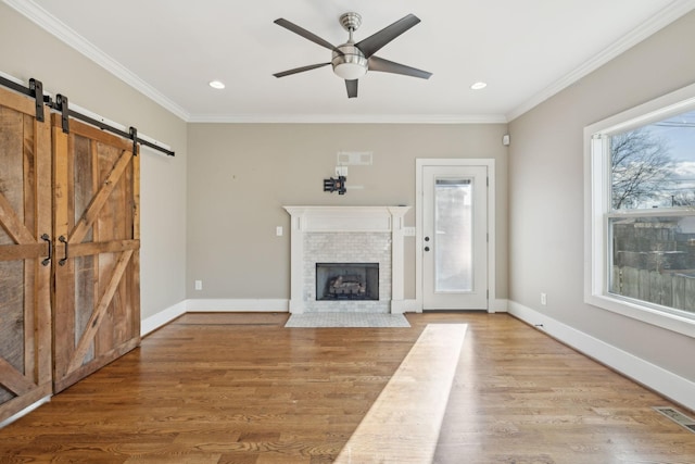 unfurnished living room featuring hardwood / wood-style flooring, ceiling fan, a healthy amount of sunlight, and ornamental molding