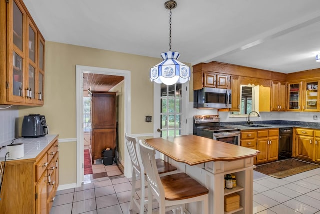 kitchen featuring hanging light fixtures, a breakfast bar, sink, appliances with stainless steel finishes, and light tile patterned flooring