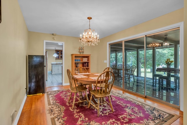 dining space with hardwood / wood-style flooring and a notable chandelier