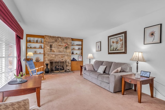 living room with a stone fireplace, carpet floors, and built in shelves