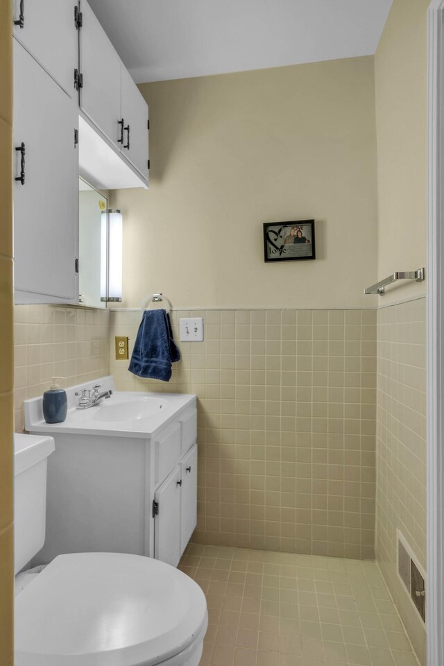 bathroom featuring vanity, tile walls, and toilet