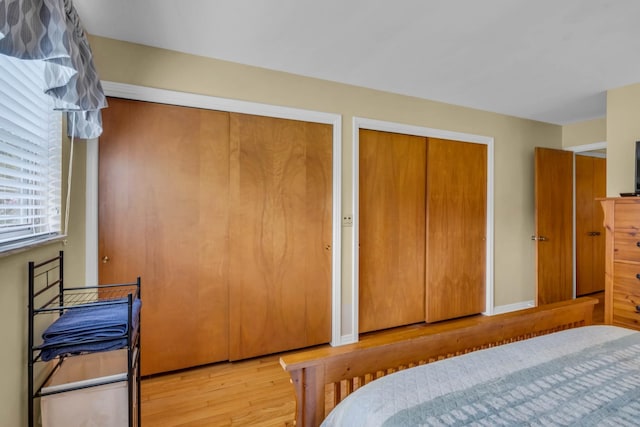 bedroom featuring light wood-type flooring and multiple closets