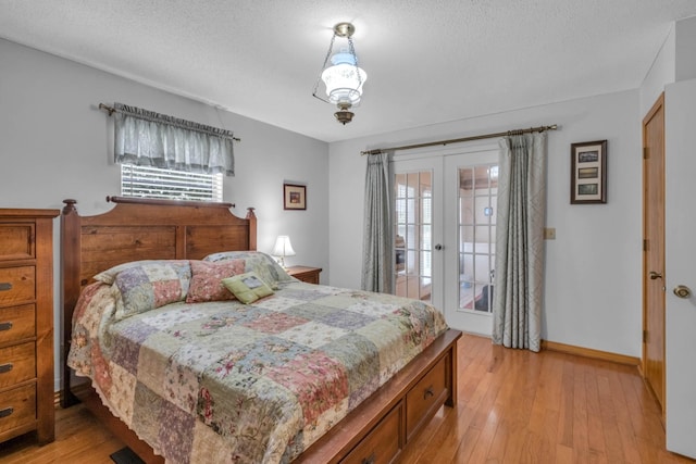 bedroom with multiple windows, access to exterior, french doors, and light hardwood / wood-style flooring