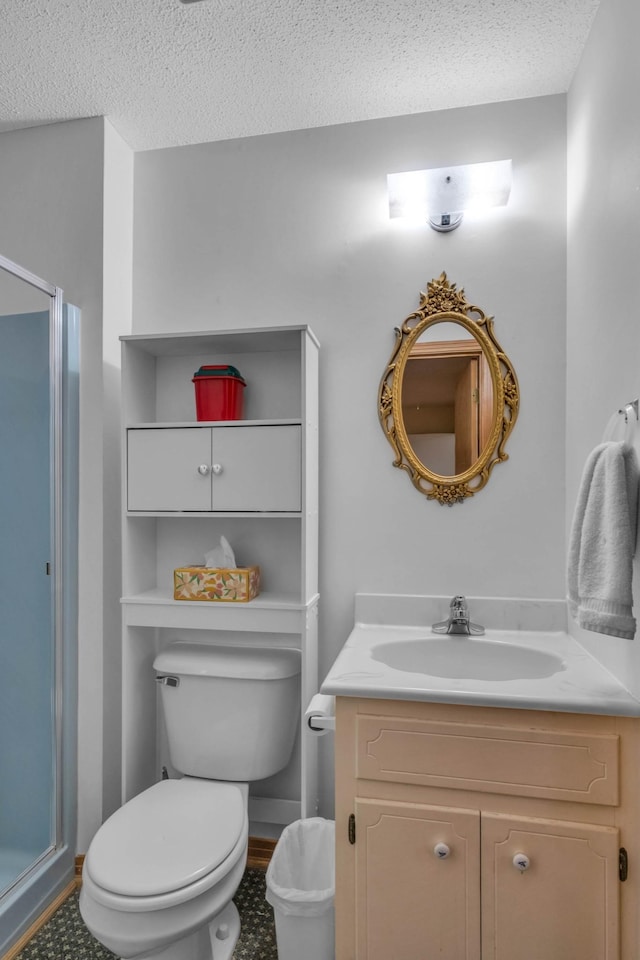 bathroom featuring a textured ceiling, toilet, vanity, and a shower with shower door