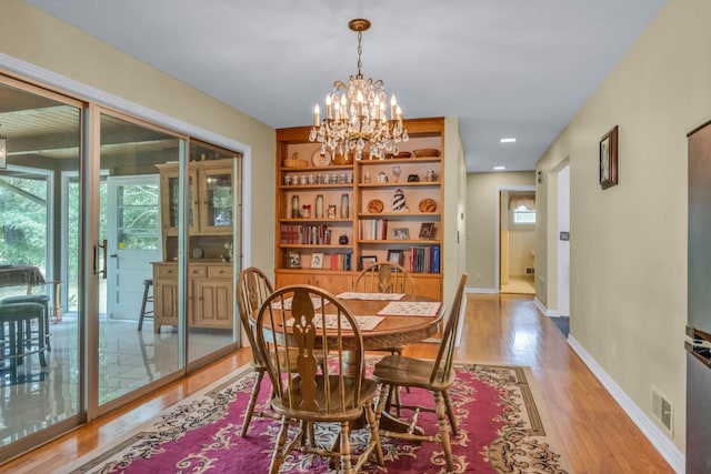 dining space featuring light wood-type flooring and a notable chandelier