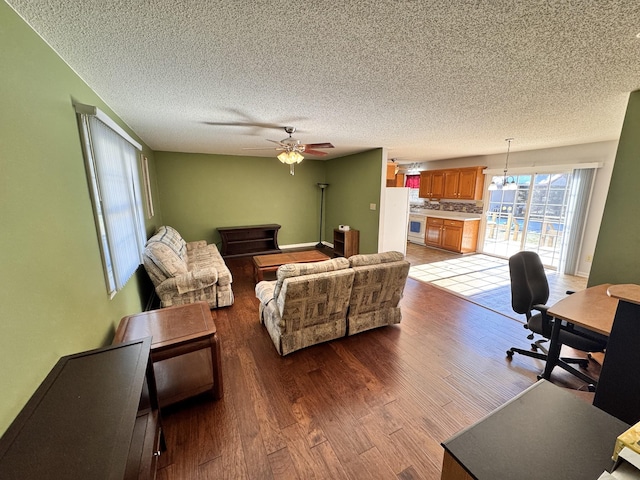 living room featuring ceiling fan, wood-type flooring, and a textured ceiling