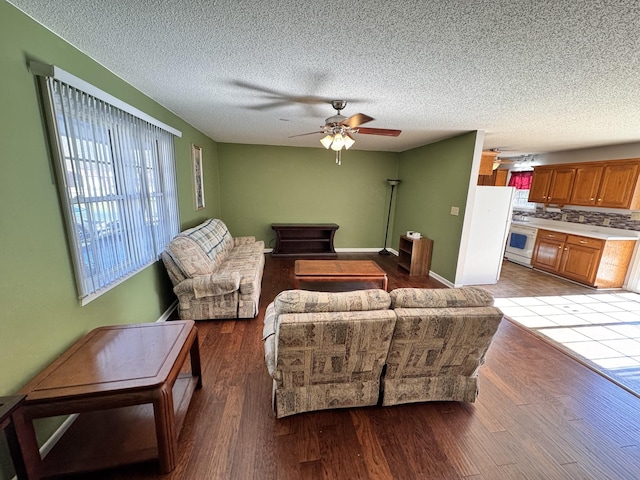 living room featuring ceiling fan, light hardwood / wood-style flooring, and a textured ceiling