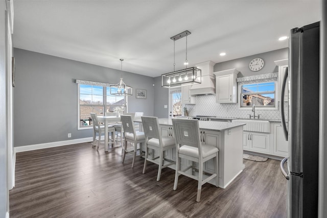 kitchen featuring sink, hanging light fixtures, stainless steel fridge, a breakfast bar area, and a kitchen island