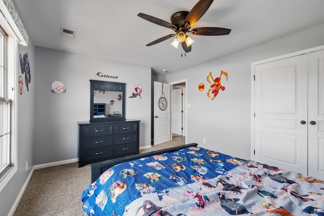 carpeted bedroom with ceiling fan, multiple windows, and a closet