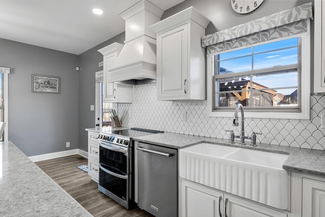 kitchen featuring premium range hood, dark wood-type flooring, sink, appliances with stainless steel finishes, and white cabinetry