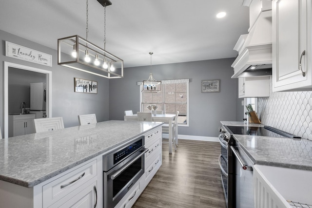 kitchen with premium range hood, stainless steel appliances, pendant lighting, a center island, and white cabinetry