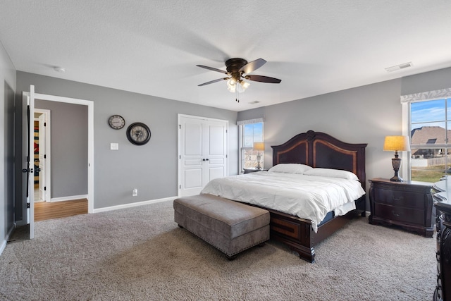 bedroom with ceiling fan, a closet, carpet, and a textured ceiling