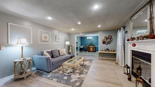 living room featuring light wood-type flooring, a textured ceiling, and ornamental molding