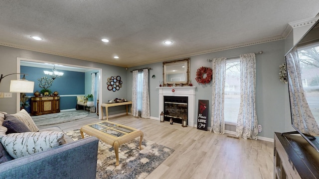 living room with a notable chandelier, ornamental molding, a textured ceiling, and light wood-type flooring