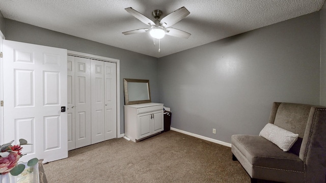 sitting room featuring a textured ceiling, light colored carpet, and ceiling fan