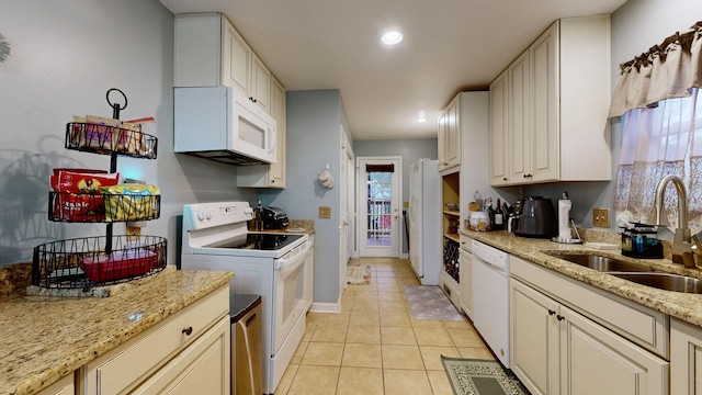 kitchen featuring light stone countertops, white appliances, sink, light tile patterned floors, and white cabinets