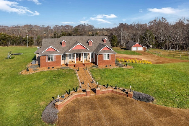 view of front of house with a front yard, a porch, a garage, and an outdoor structure