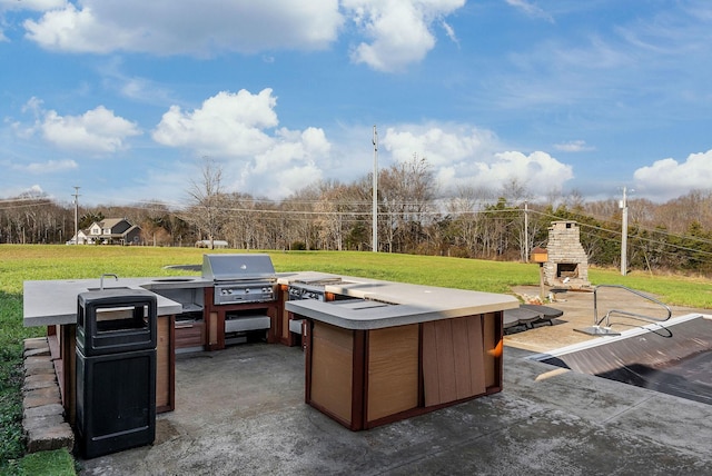 view of patio / terrace with an outdoor stone fireplace and area for grilling